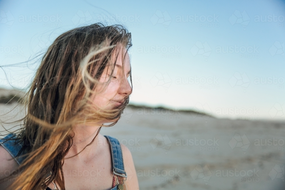 Carefree teenage girl on the beach with messy hair blowing in the wind - Australian Stock Image