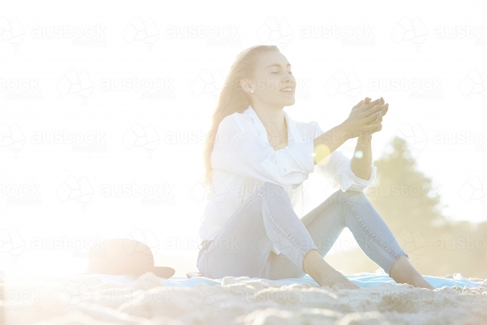 Carefree young blonde-haired woman at beach enjoying the sunshine - Australian Stock Image