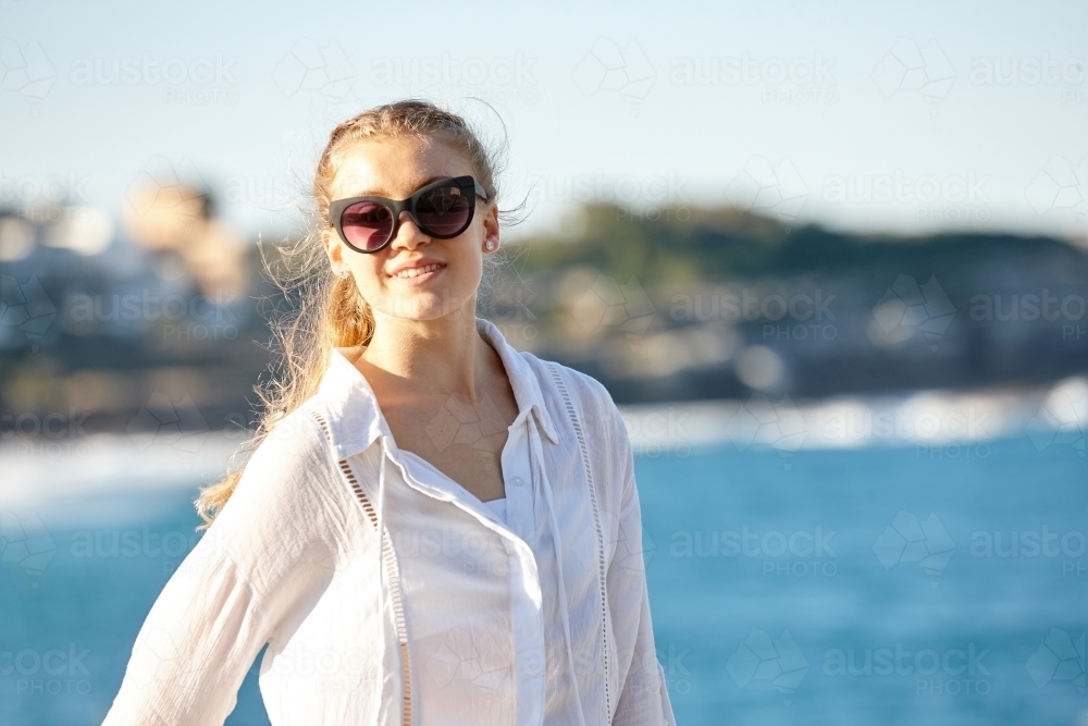 Carefree young blonde-haired woman at beach wearing sunglasses - Australian Stock Image