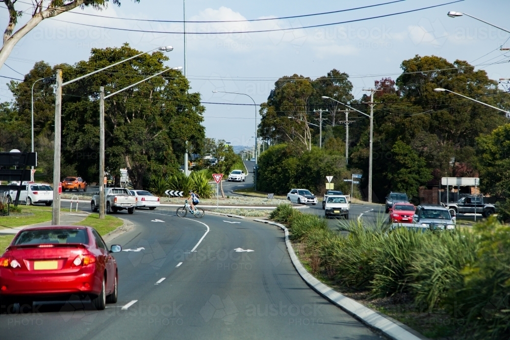 Cars and cyclist approaching a large roundabout in heavy traffic - Australian Stock Image
