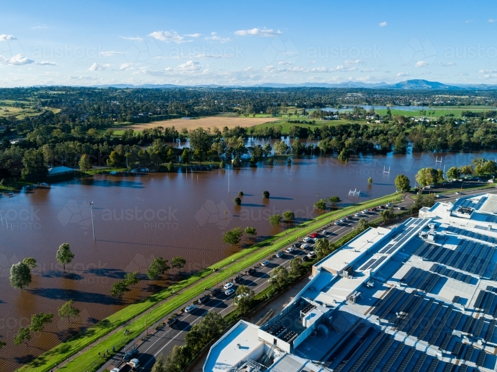 Cars and sightseers watching floodwater rising up towards levee bank - Australian Stock Image