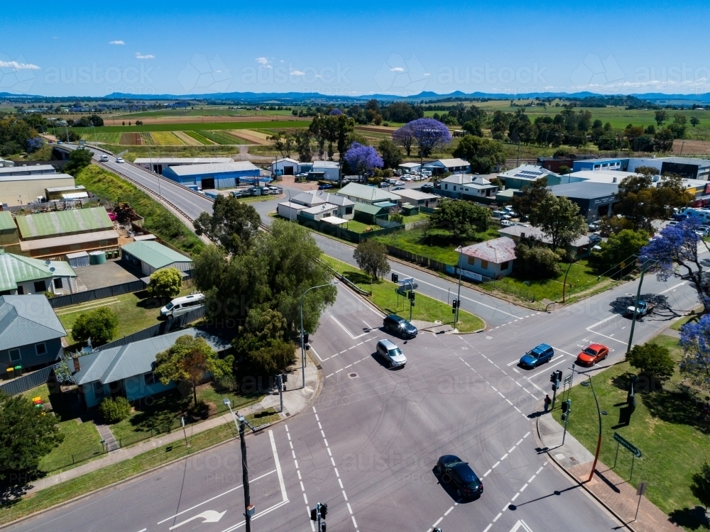 cars at intersection and traffic lights coming into Singleton in bright sunlight - Australian Stock Image