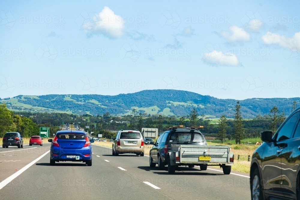 Cars driving along a highway p plater and car with trailer - Australian Stock Image