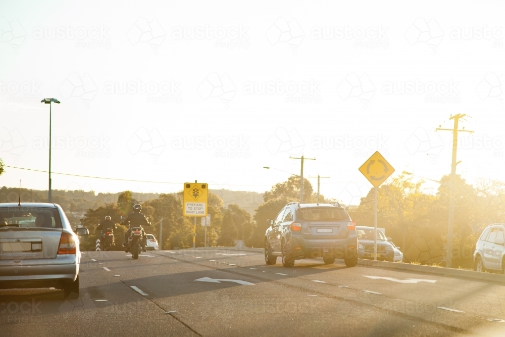 Cars in peak hour traffic approaching traffic lights on road in the afternoon - Australian Stock Image