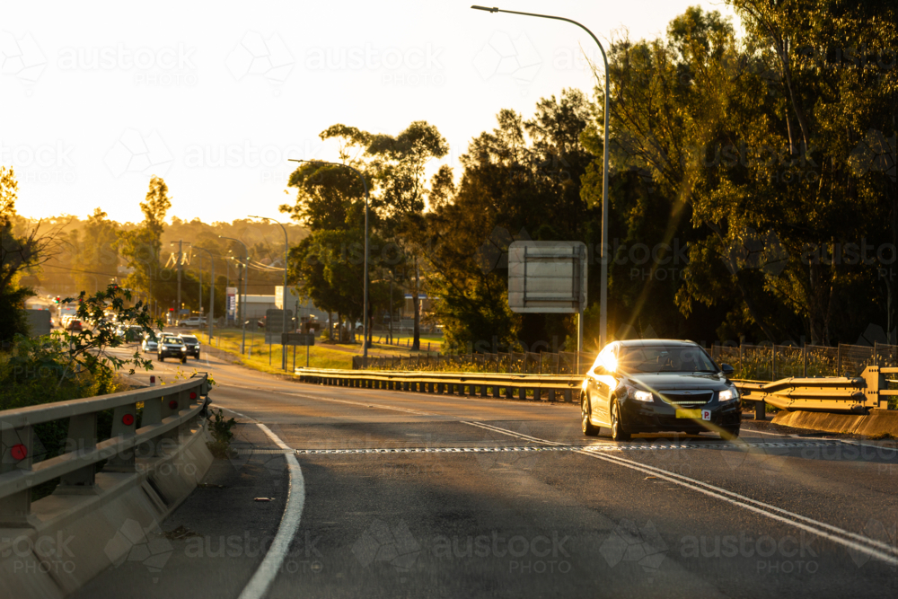 Cars on New England Highway in Singleton in golden sunset light - Australian Stock Image