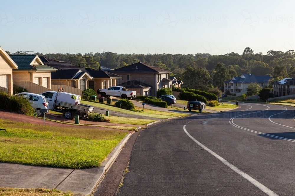Cars parked in driveways of houses beside suburban road - Australian Stock Image