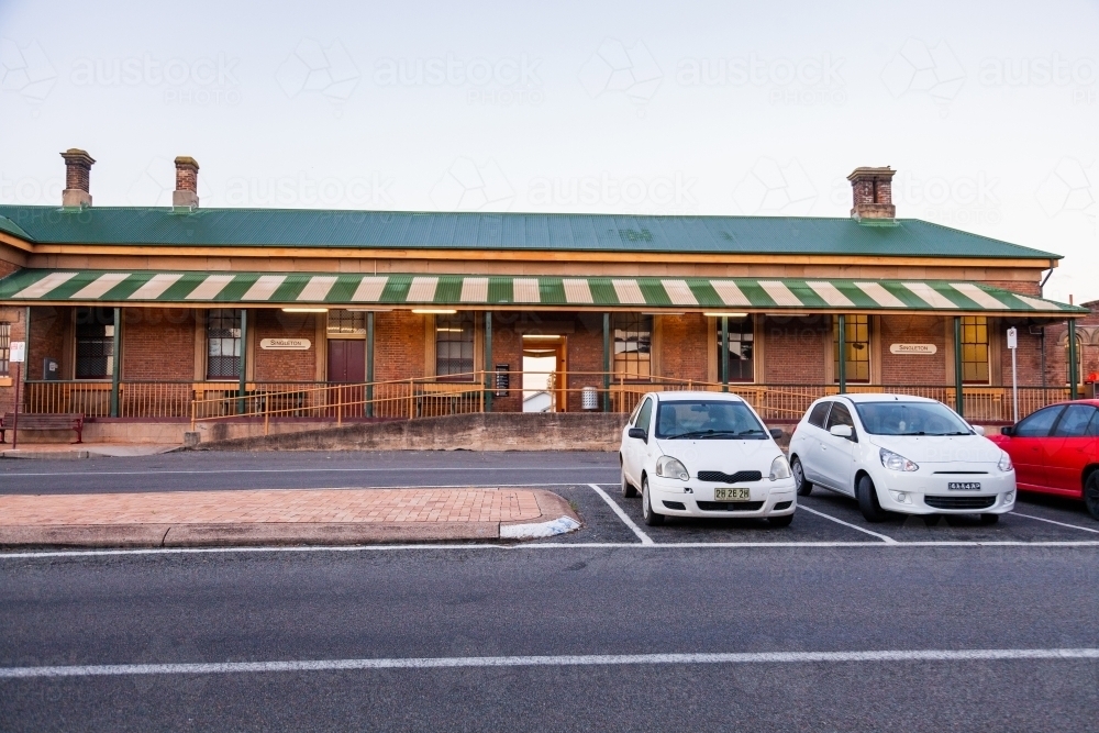 cars parked in the center of the road in front of country train station - Australian Stock Image
