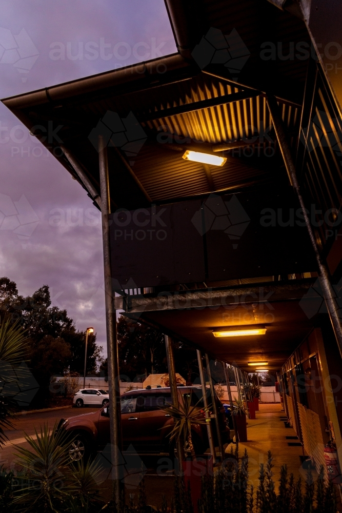 Cars parked outside shop front with warm lights. - Australian Stock Image