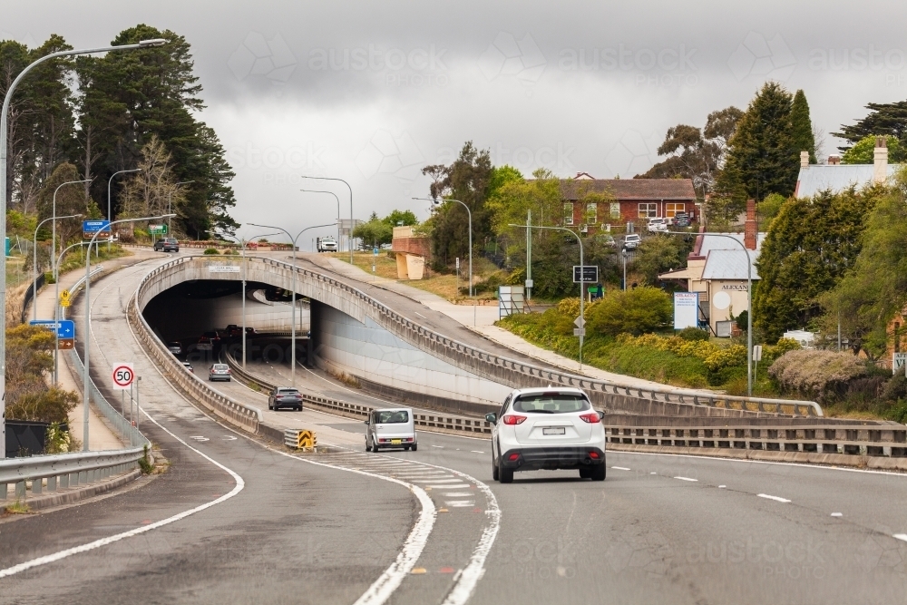 Cars traveling under arching bridge over road - Australian Stock Image