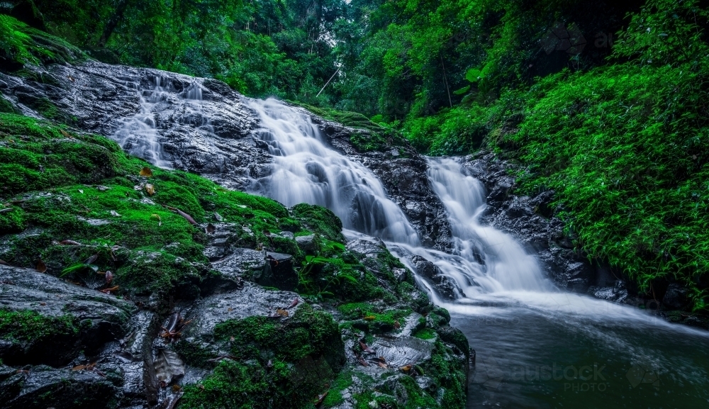 Cascading waterfall over green mossy rocks - Australian Stock Image
