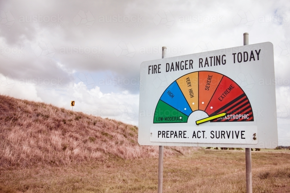 Catastrophic fire danger rating sign with dry grass and cloudy sky - Australian Stock Image