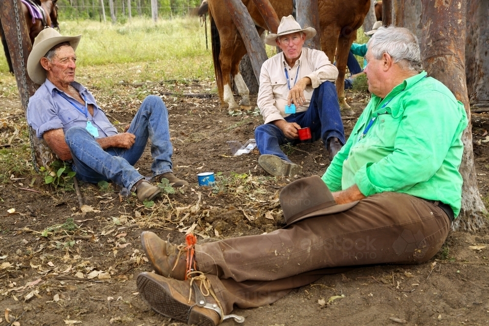 Image of Cattle drovers sitting resting against trees at smoko