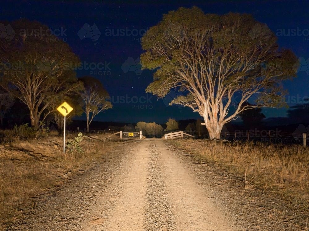 Cattle grid on a gravel road at night in car headlights - Australian Stock Image