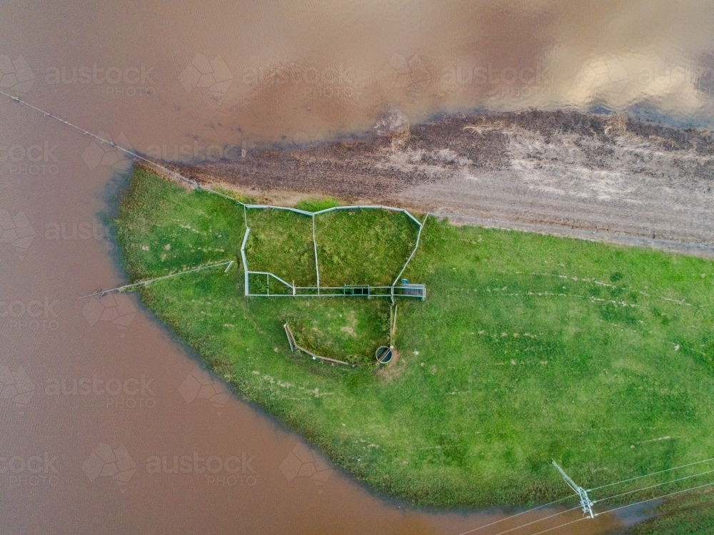 Cattle yards on high ground with floodwaters rising up on Australian farm - Australian Stock Image