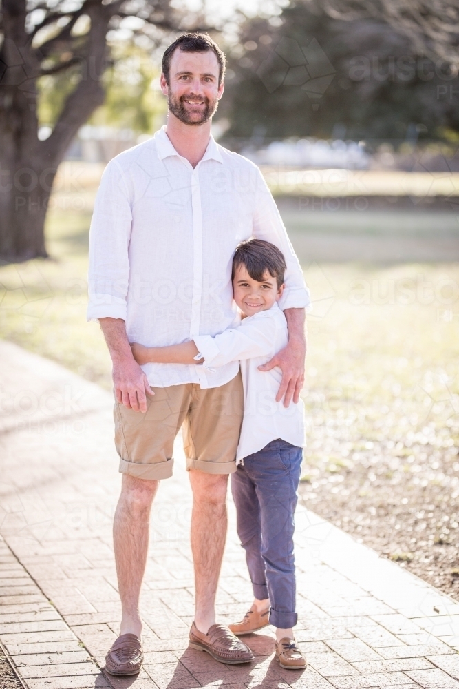 Caucasian father standing with arm around mixed race aboriginal son - Australian Stock Image