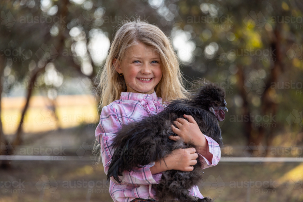 Caucasian girl holding Silkie chicken with gentle affection - Australian Stock Image