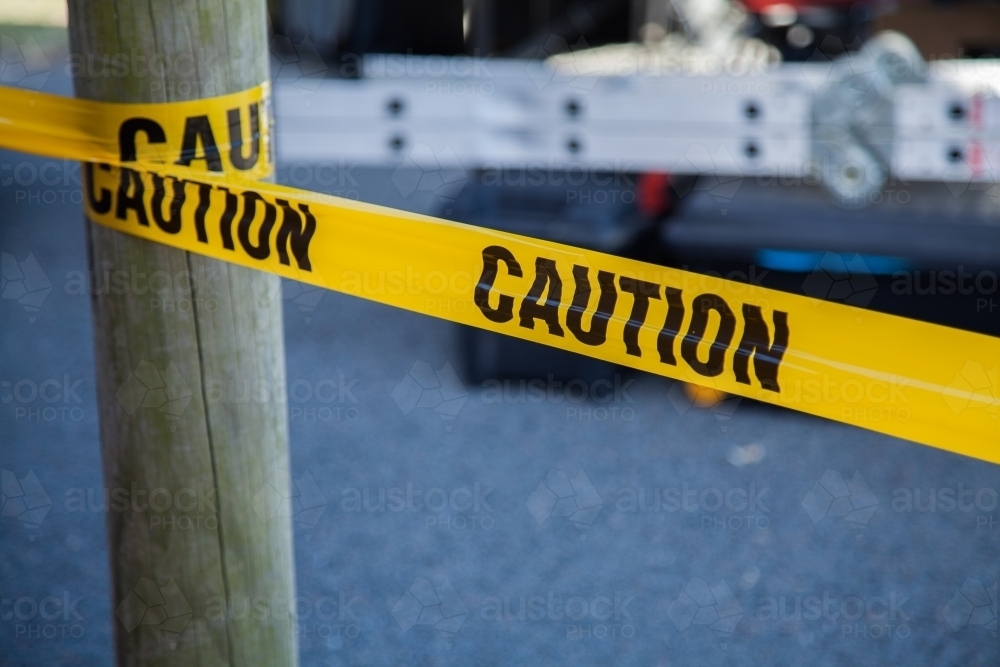 Caution tape around a post with ladder behind - Australian Stock Image