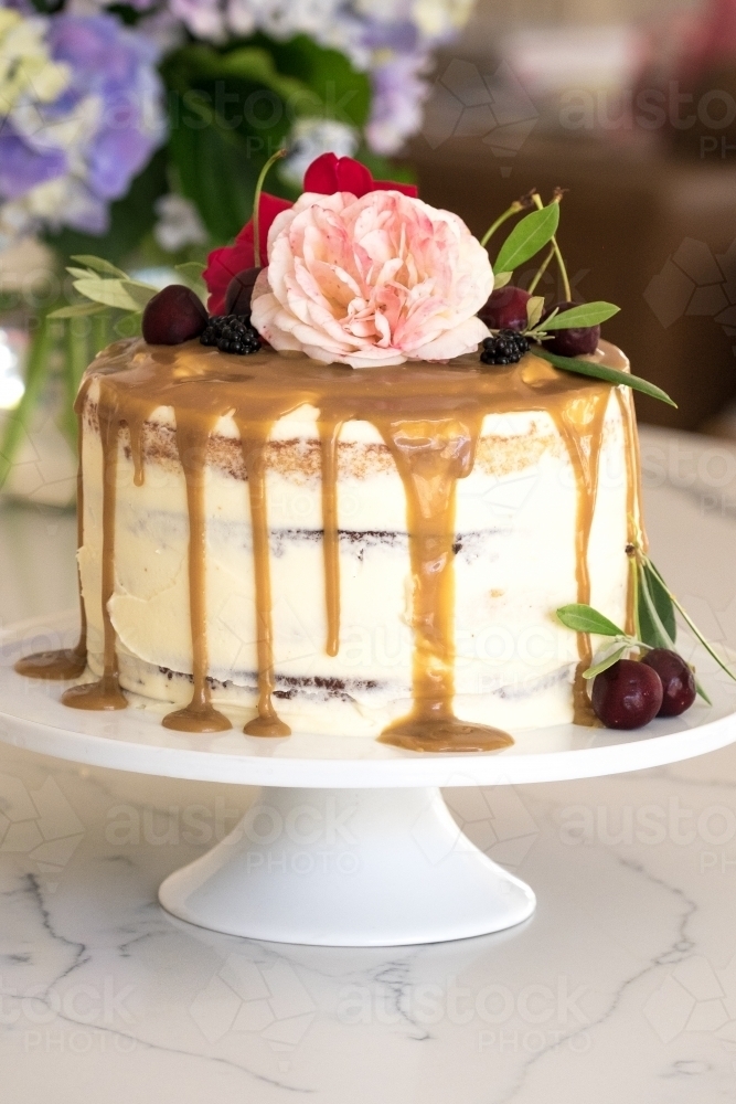 Celebration cake styled with flowers and cherries - Australian Stock Image