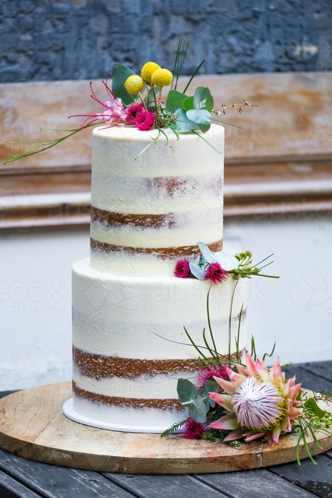 Celebration white layer cake with flowers on table - Australian Stock Image
