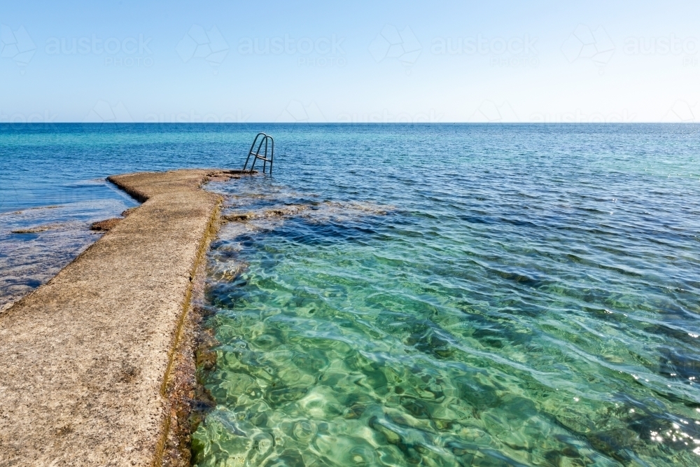 cement path to steps into blue sea - Australian Stock Image
