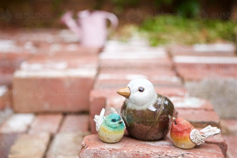 Ceramic bird statuettes of birds sittings on a pile of bricks - Australian Stock Image