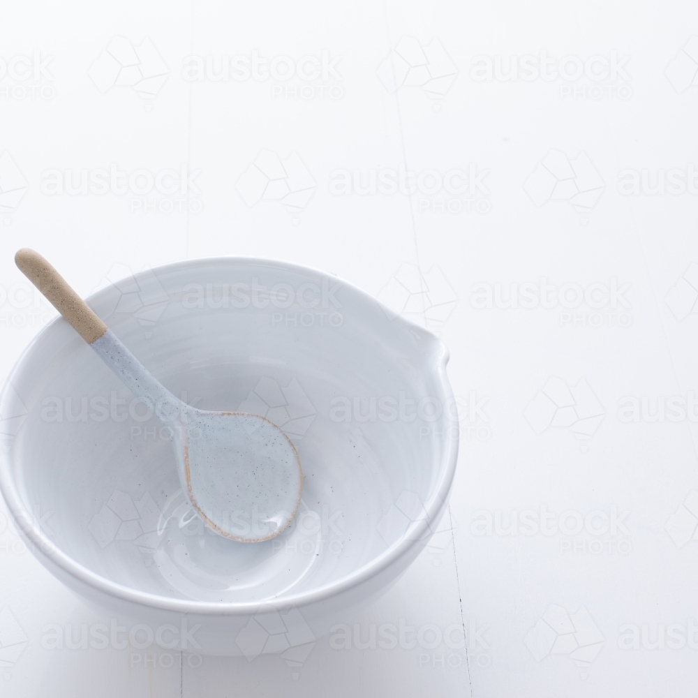 Ceramic mixing bowl and spoon on white background - Australian Stock Image