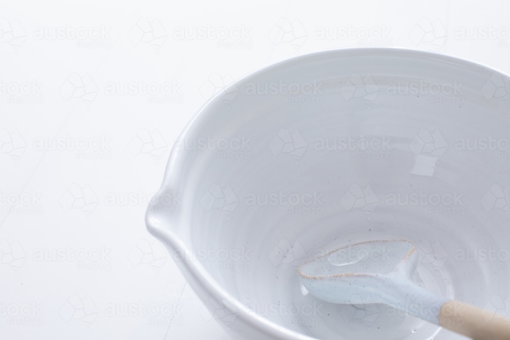 Ceramic mixing bowl and spoon on white background - Australian Stock Image