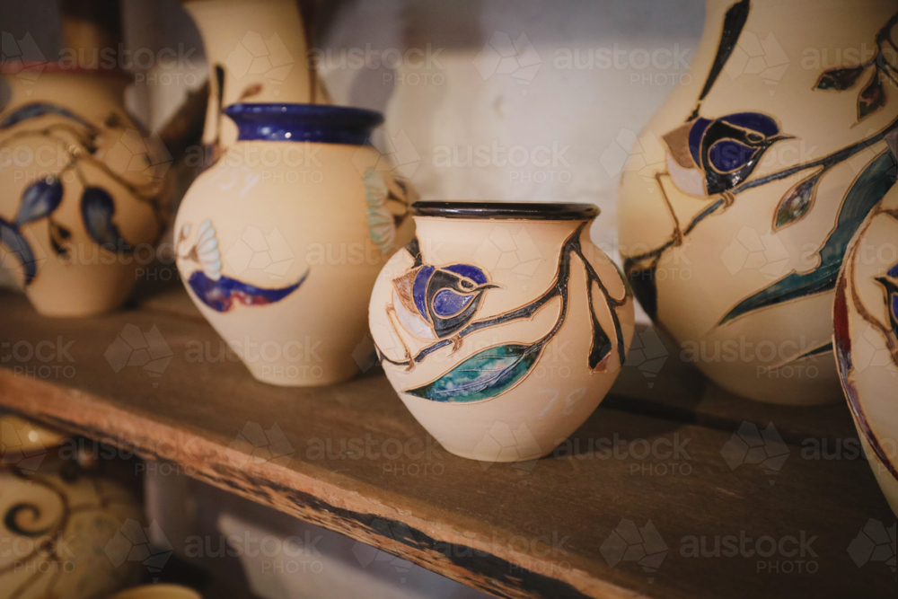 Ceramic vases with hand-painted florals on a rustic wooden shelf - Australian Stock Image