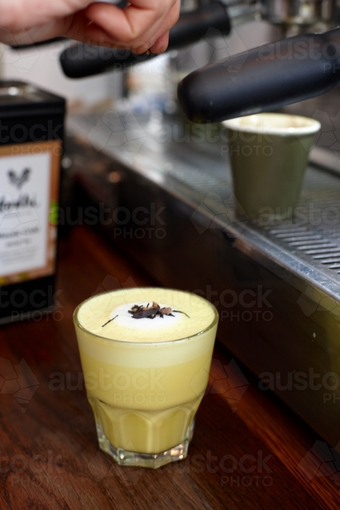 Chai and turmeric latte being prepared in cafe kitchen - Australian Stock Image