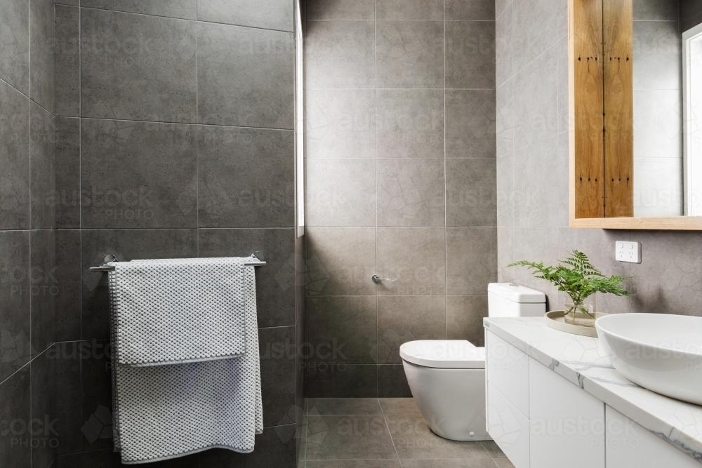 Charcoal grey bathroom with marble benchtop and wood mirror - Australian Stock Image