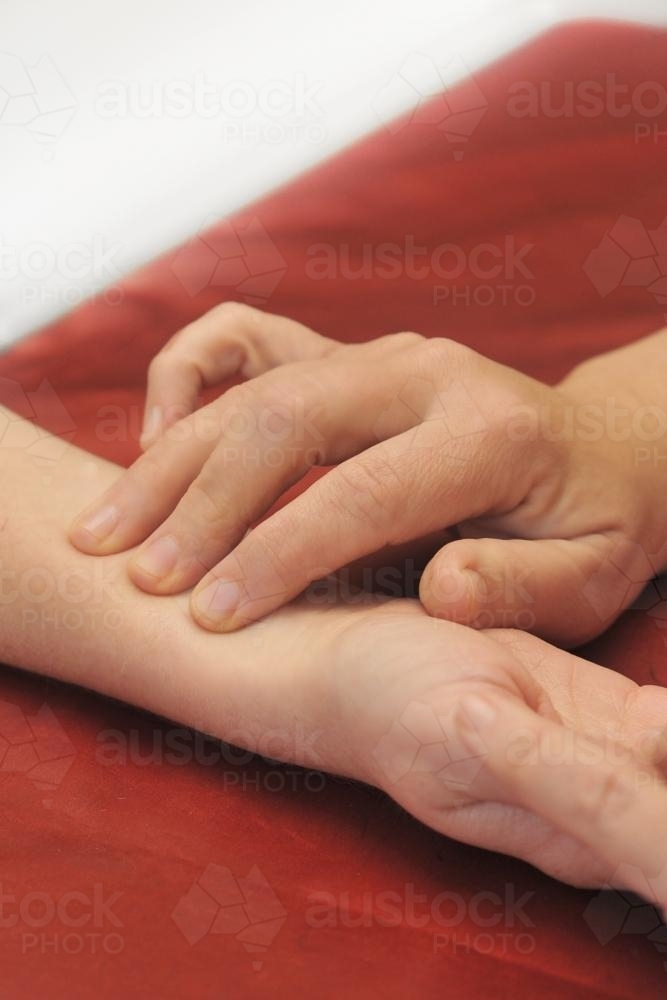 checking a patient's pulse at a holistic spa - Australian Stock Image