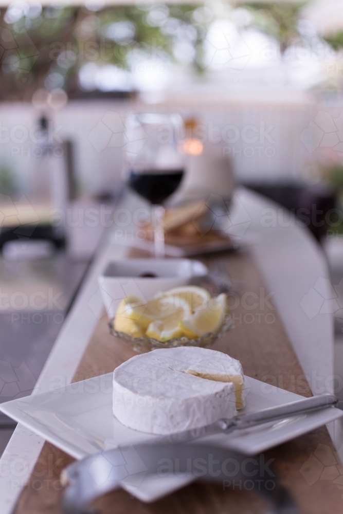Cheese platter with a bowl of sliced lemons and glass of red wine - Australian Stock Image