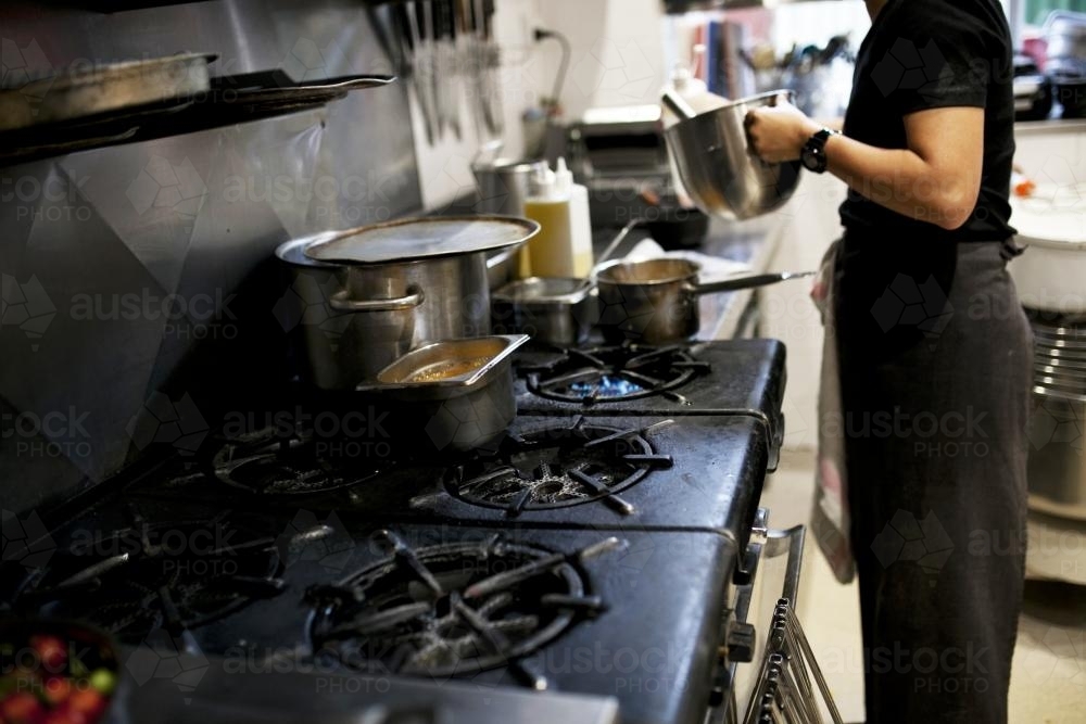 Chef cooking in cafe kitchen - Australian Stock Image