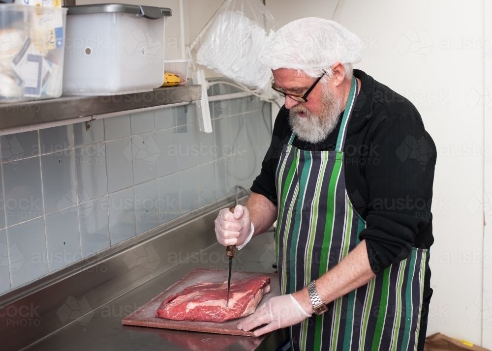 chef cutting meat in a commercial kitchen - Australian Stock Image