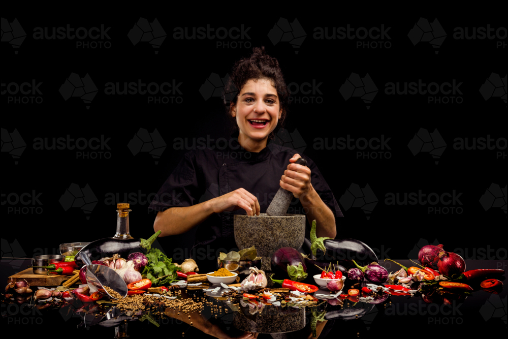 Chef portrait, pounding spices with a mortar and pestle, making curry - Australian Stock Image