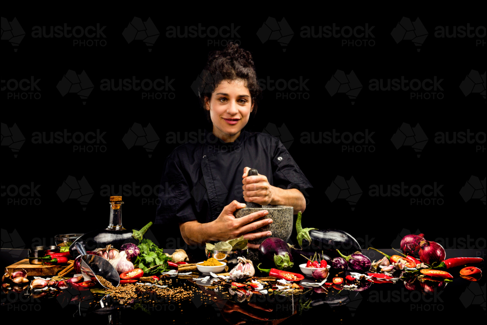 Chef portrait, pounding spices with a mortar and pestle, making curry - Australian Stock Image