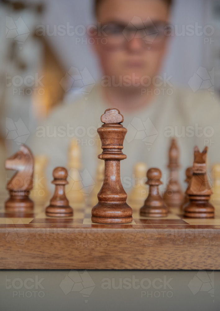 Chess board with teen boy in the background - Australian Stock Image