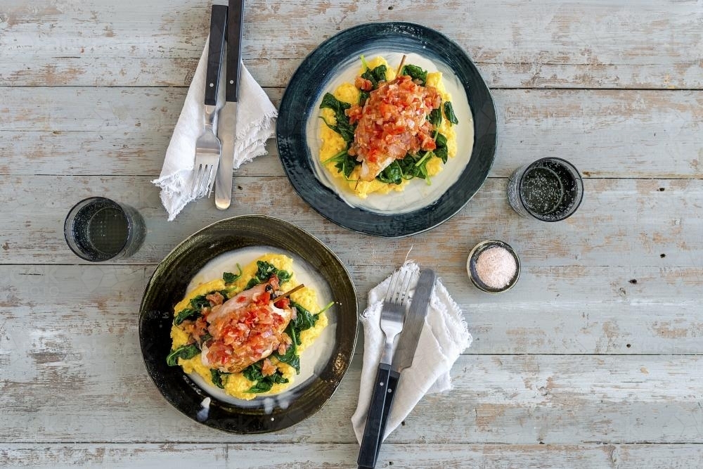 Chicken and omelette with spinach laid on table seen from above - Australian Stock Image