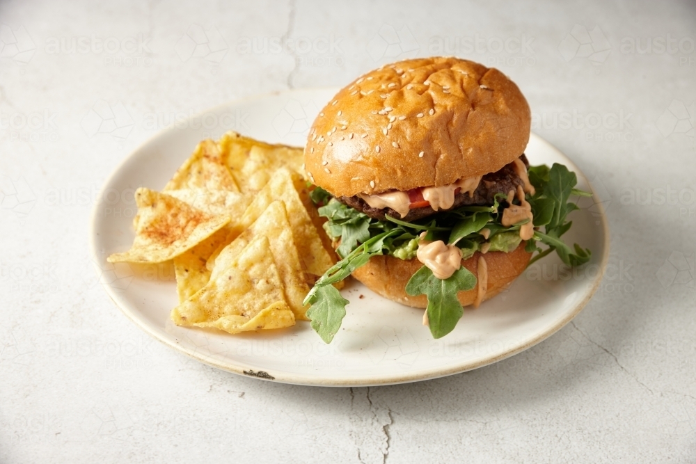 Chicken burger with corn chips on plate - Australian Stock Image