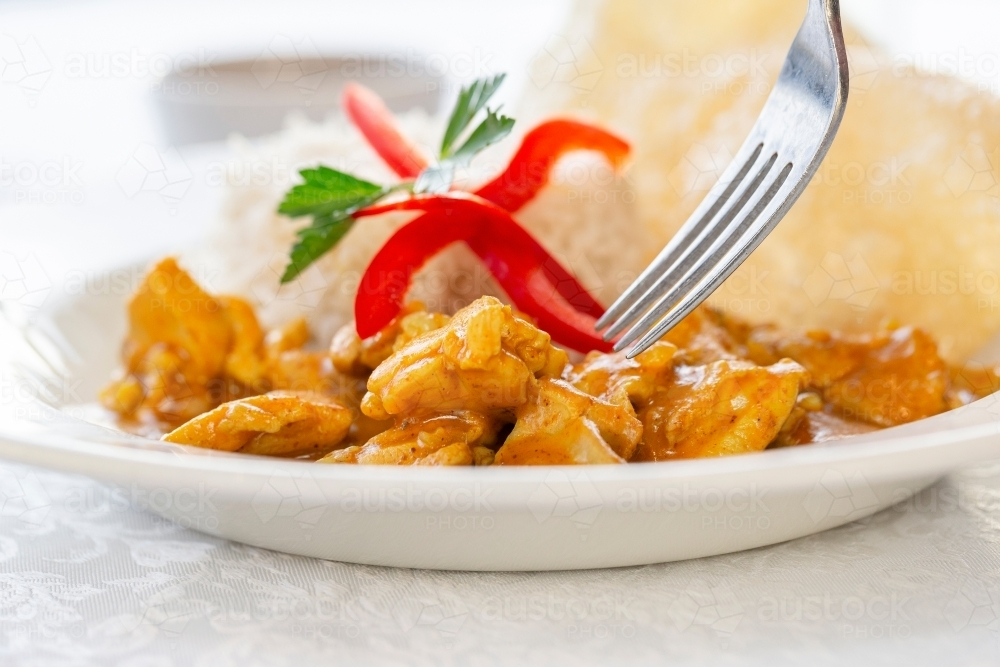Chicken curry served with rice garnished with red pepper and fresh parsley. - Australian Stock Image