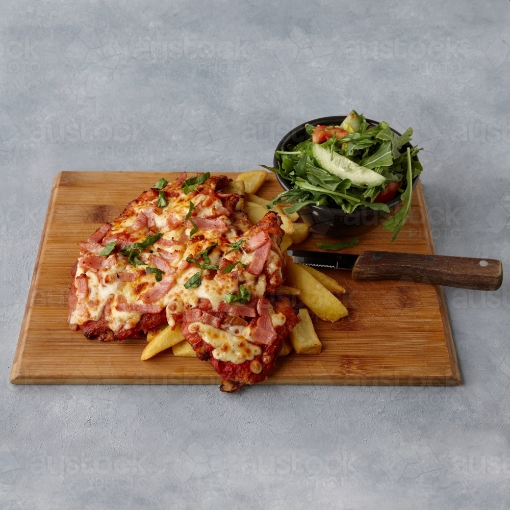 Chicken parmigiana with salad on table - Australian Stock Image