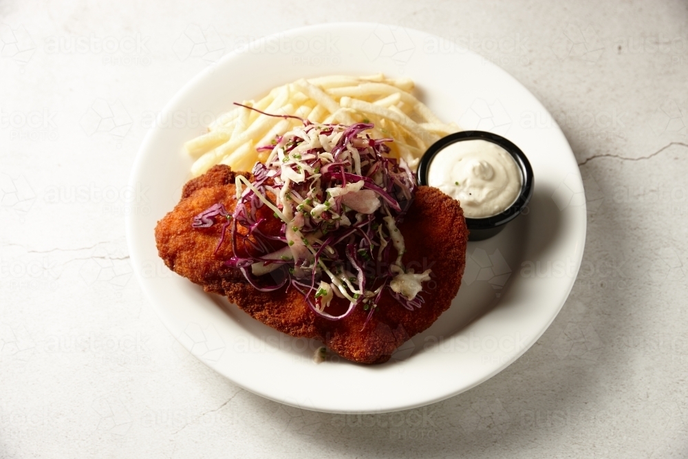 Chicken schnitzel with salad and fries on plate - Australian Stock Image