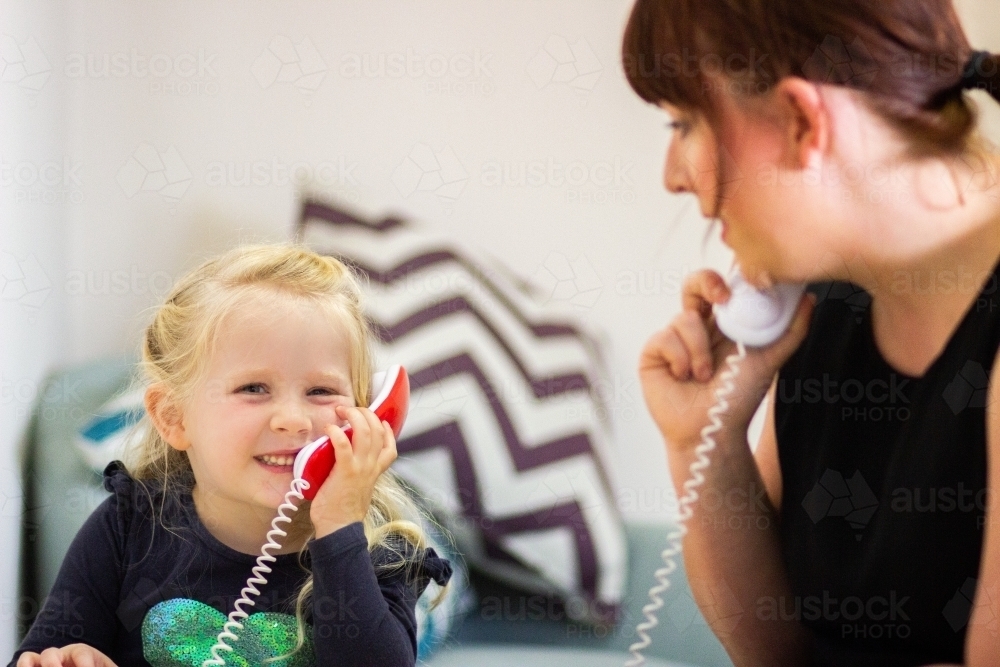 Child and adult playing on toy phones in speech clinic - Australian Stock Image