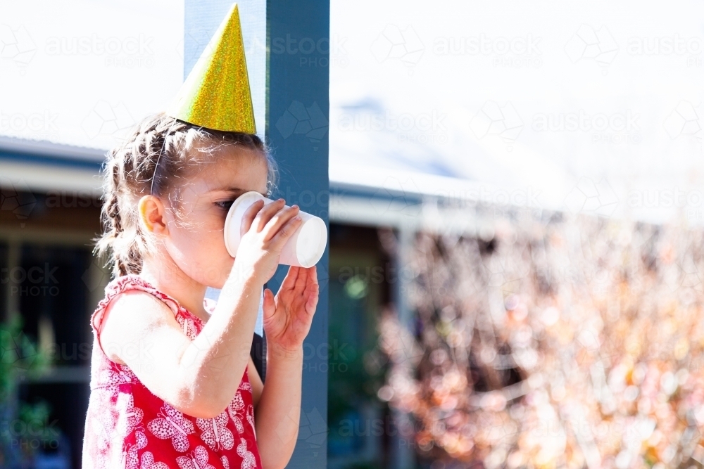 Child at party drinking water from paper cup - Australian Stock Image