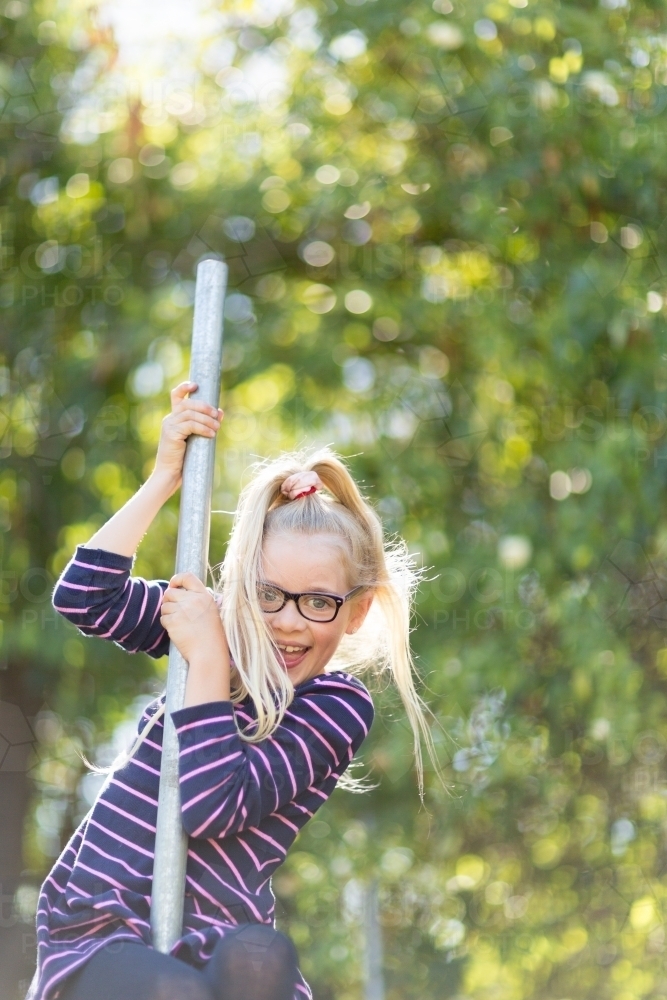 Child climbing a pole outdoors - Australian Stock Image