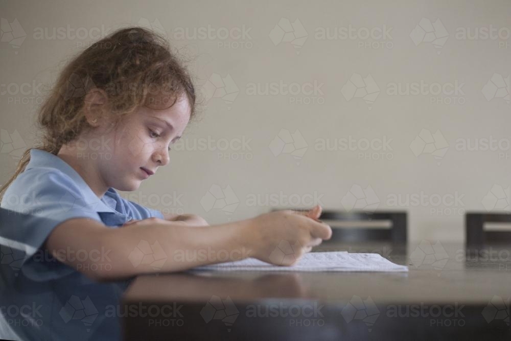 Child doing school homework at wooden desk. - Australian Stock Image