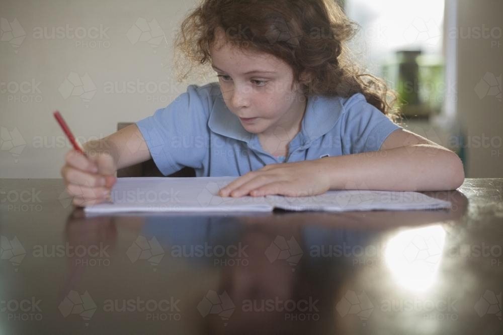 Child doing school homework at wooden desk. - Australian Stock Image