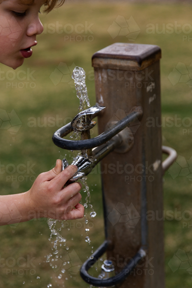 child drinking from a public water fountain - Australian Stock Image