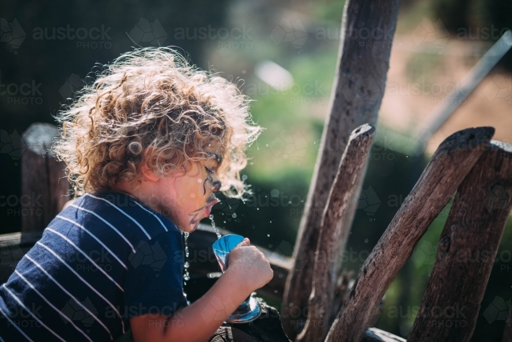 Child drinking from a tap - Australian Stock Image