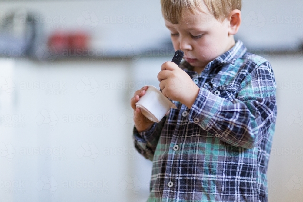 Child eating yoghurt with a spoon - Australian Stock Image
